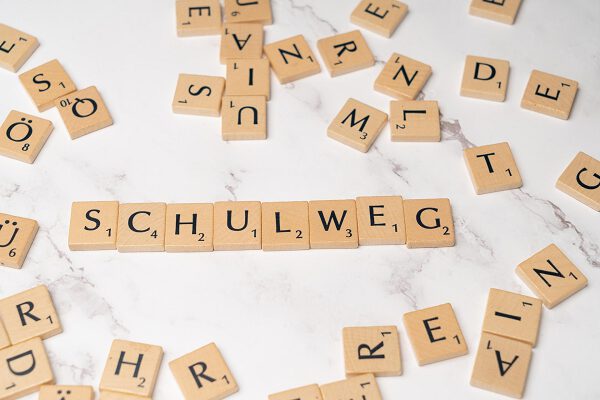 Scrabble-Steine auf einer Tischoberfläche, darunter das Wort "Schulweg"